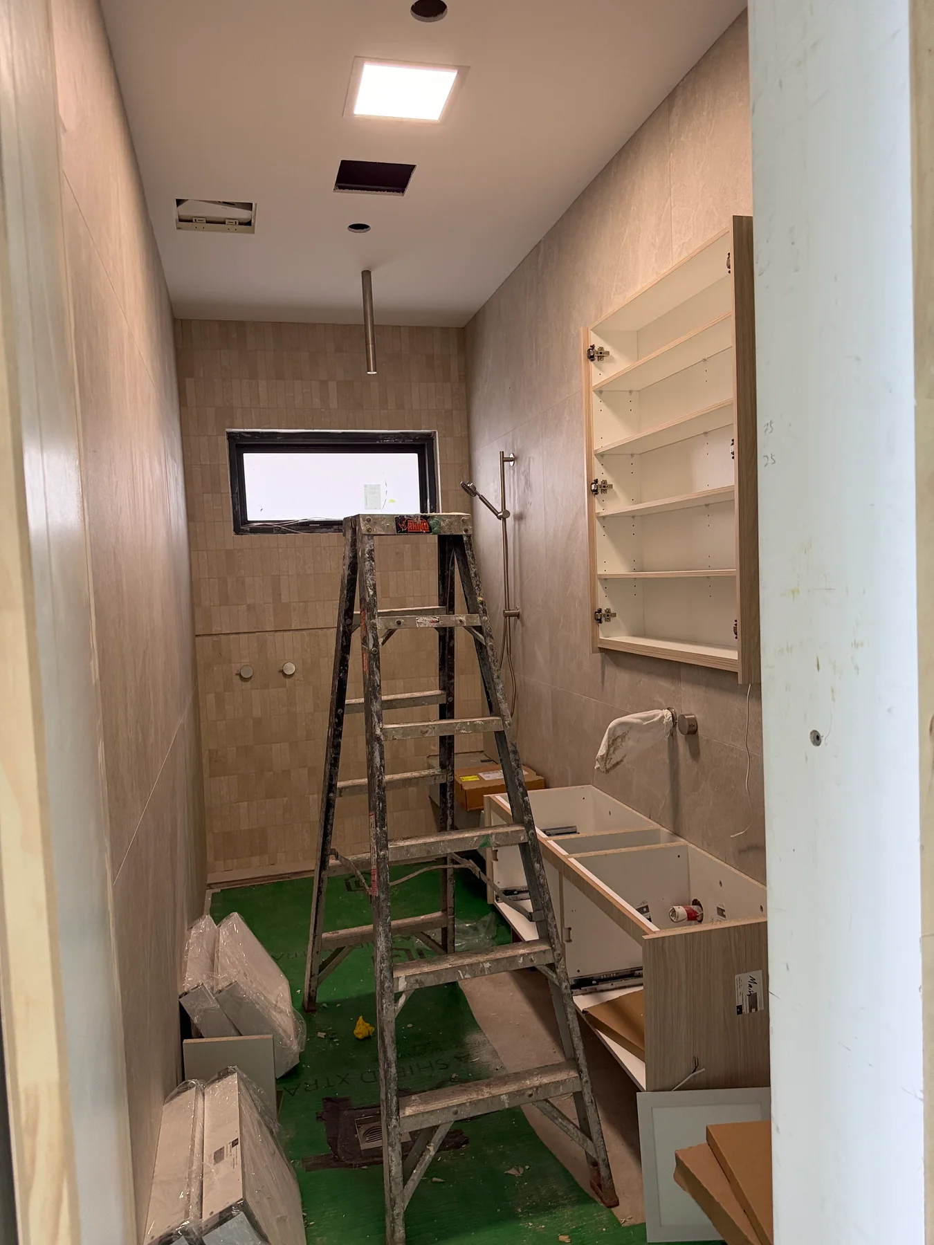 Cabinet-lined utility area in Kensington with an illuminated ceiling panel and remaining fit-out work