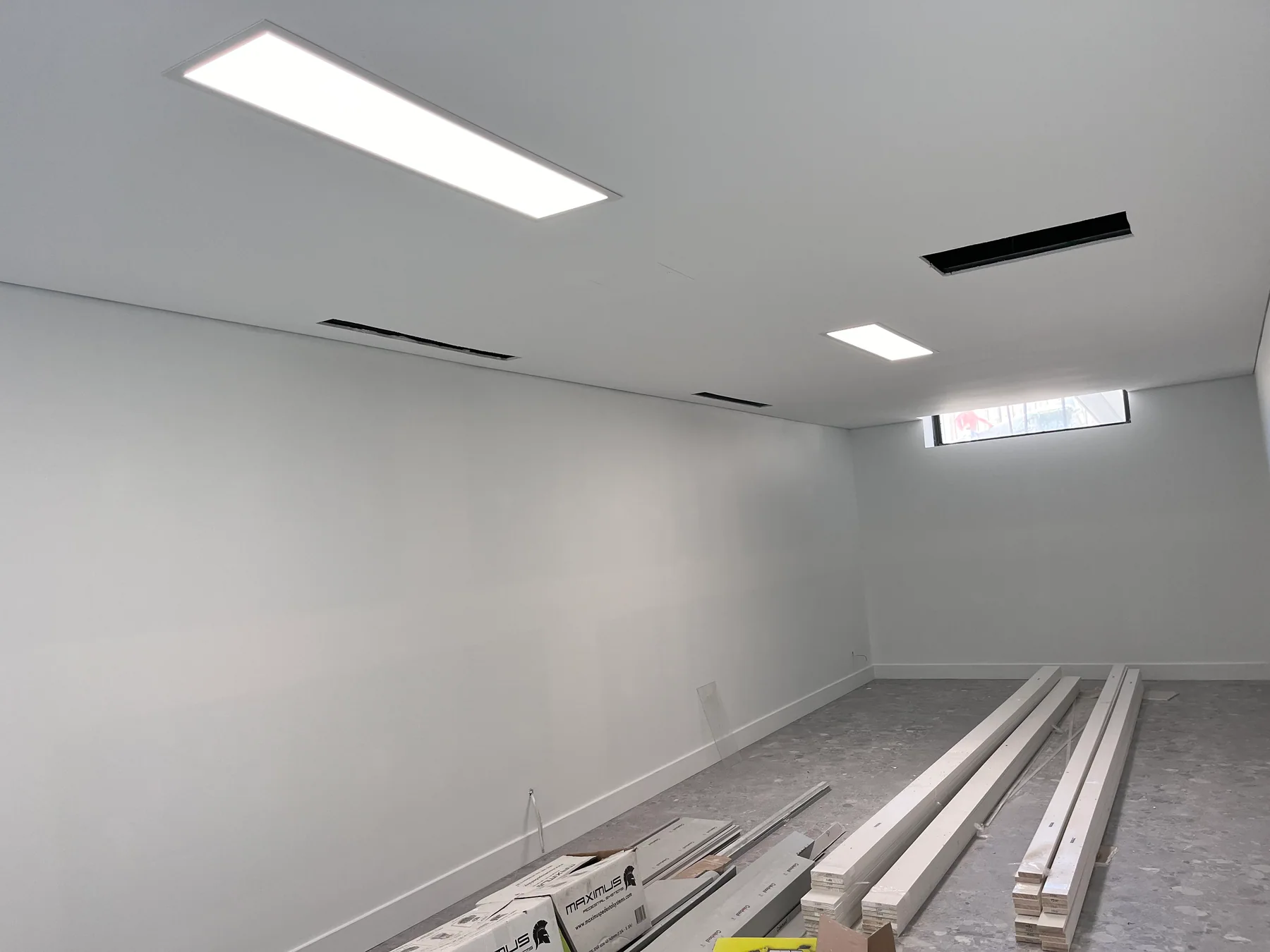 Lower-floor room with illuminated ceiling panels and remaining fit-out materials in Randwick