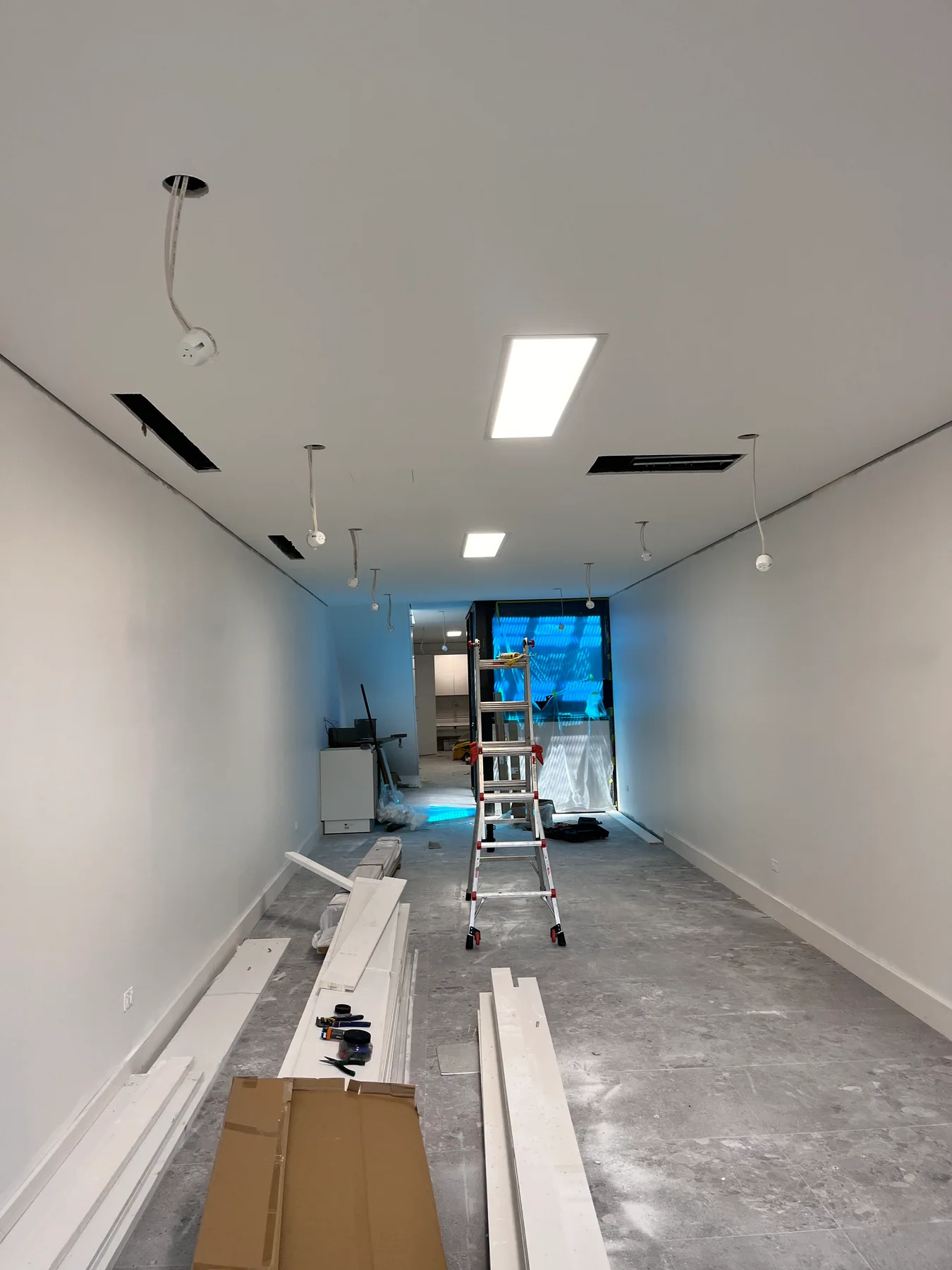 Long lower-floor hallway with ceiling panels and building materials in Randwick