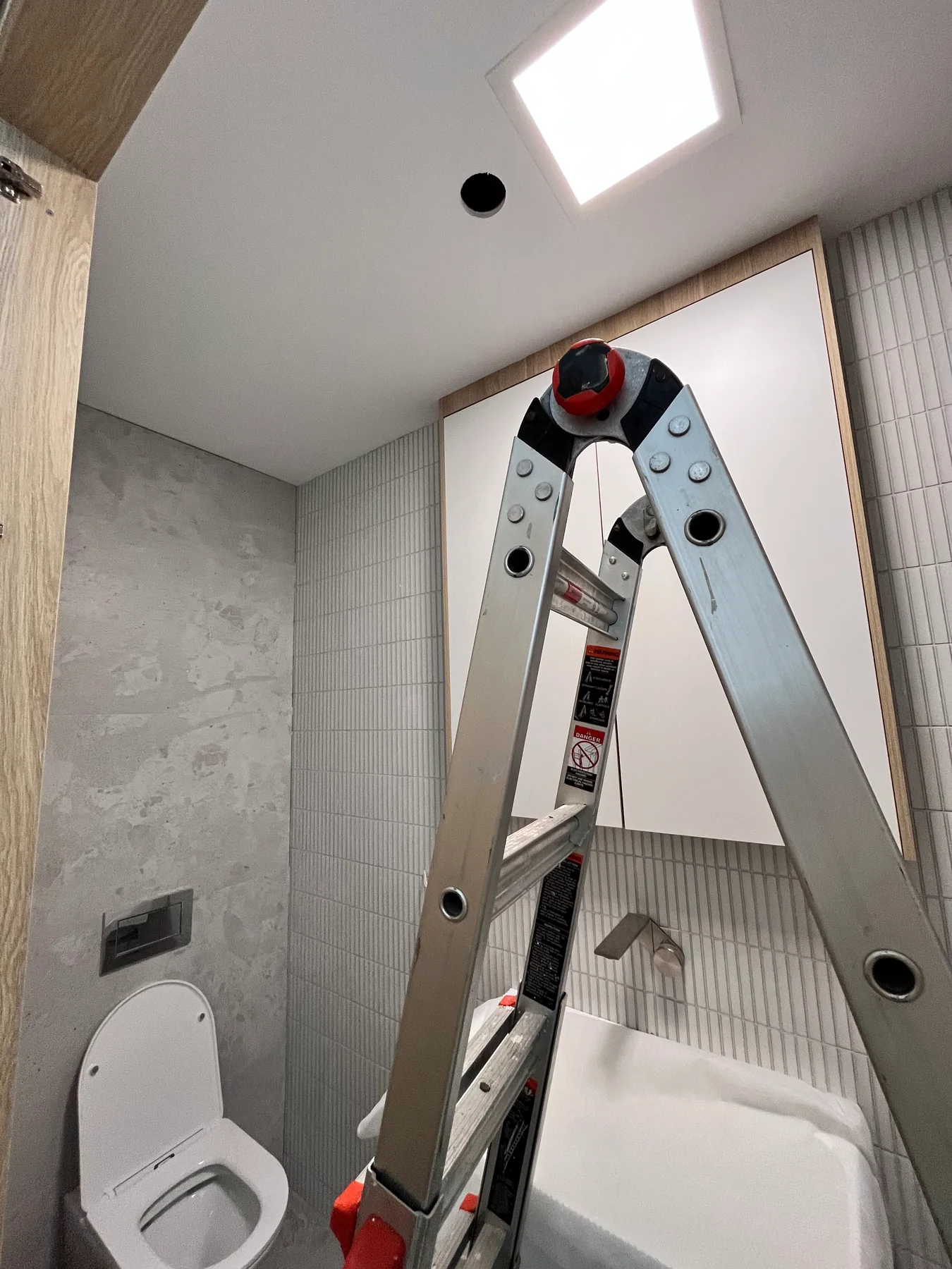 Ceiling panel in a Randwick WC during bathroom fit-out, with a ladder still in the room